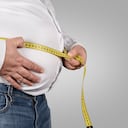 Hombre con sobrepeso midiendo su vientre con cinta métrica