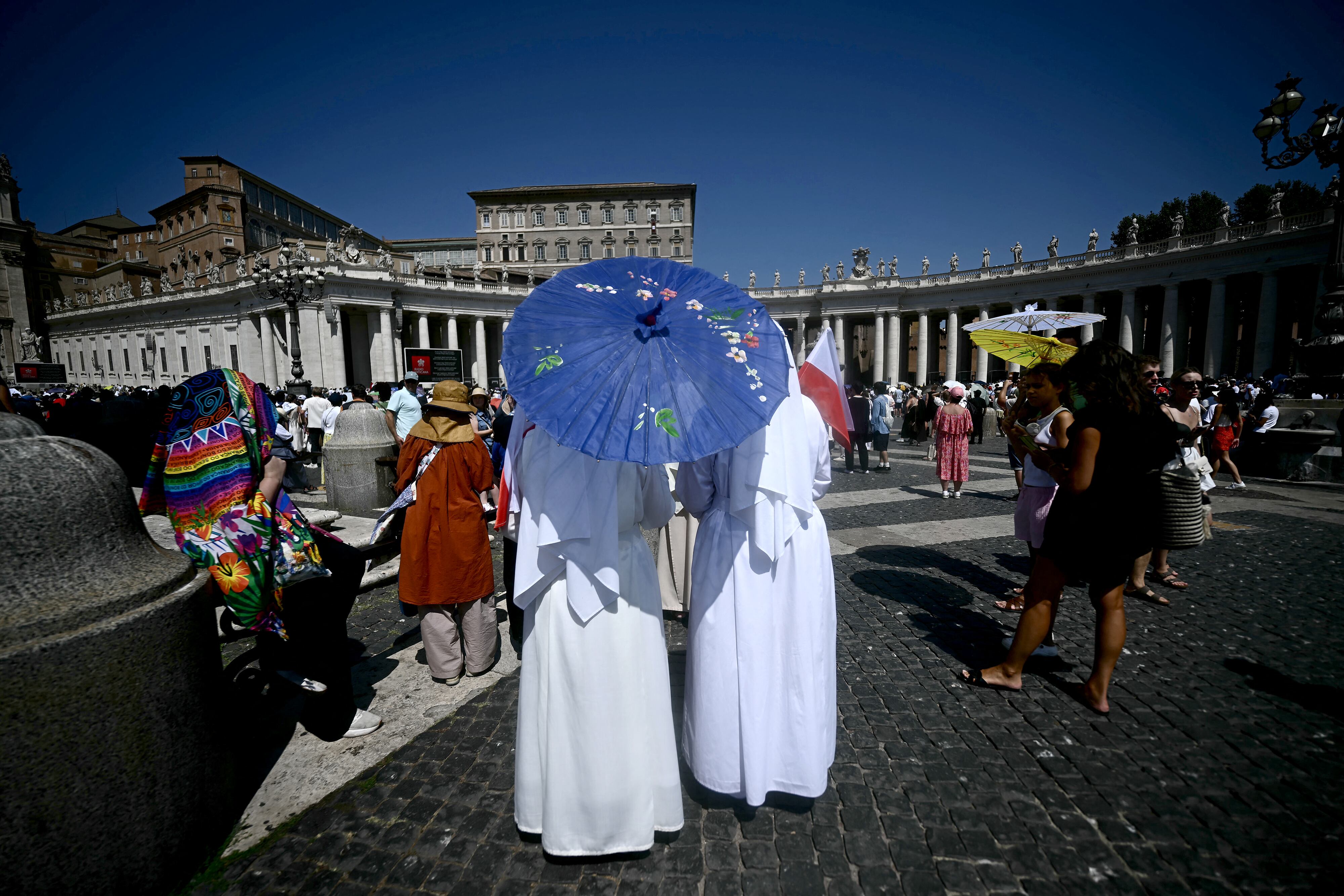 Nuns use umbrellas to shield themselves from the midday sun as they gather on St. Peter's Square at The Vatican on August 9, 2026, prior to hearing Pope Leo XIV deliver The Angelus Prayer. (Photo by Filippo MONTEFORTE / AFP)
