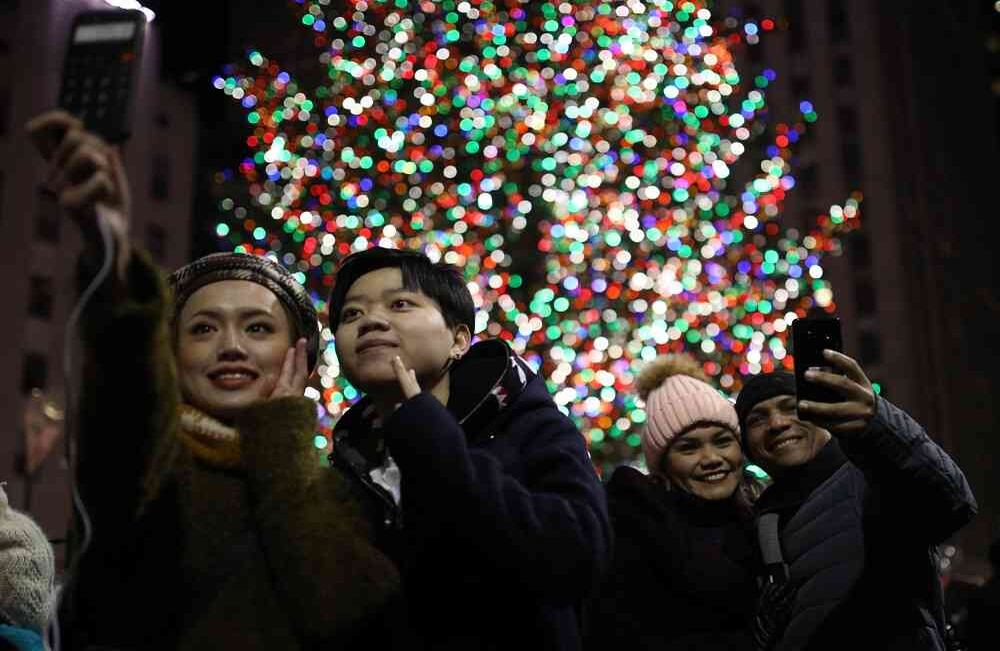 La gente toma fotos de un espectáculo de luces en Saks Fifth Avenue cerca del árbol de Navidad en el Rockefeller Center el 26 de diciembre de 2017 en la ciudad de Nueva York. El árbol de Navidad se enciende anualmente como una tradición siendo uno de los símbolos importantes de la ciudad en el Rockefeller Center. Foto: Atilgan Özdil / Agencia Anadolu