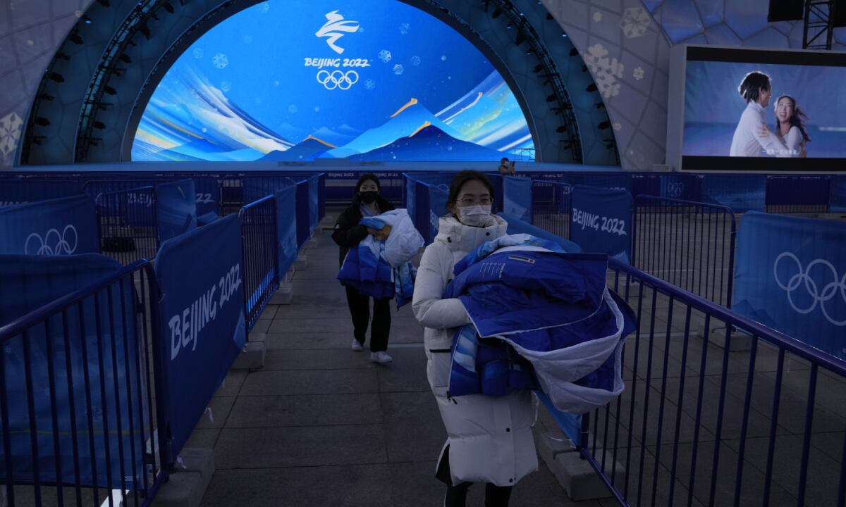 Staff members labor during a rehearsal of a victory ceremony at the Beijing Medals Plaza of the Winter Olympics in Beijing, China, Monday, Jan. 3, 2022. (AP/Ng Han Guan)
