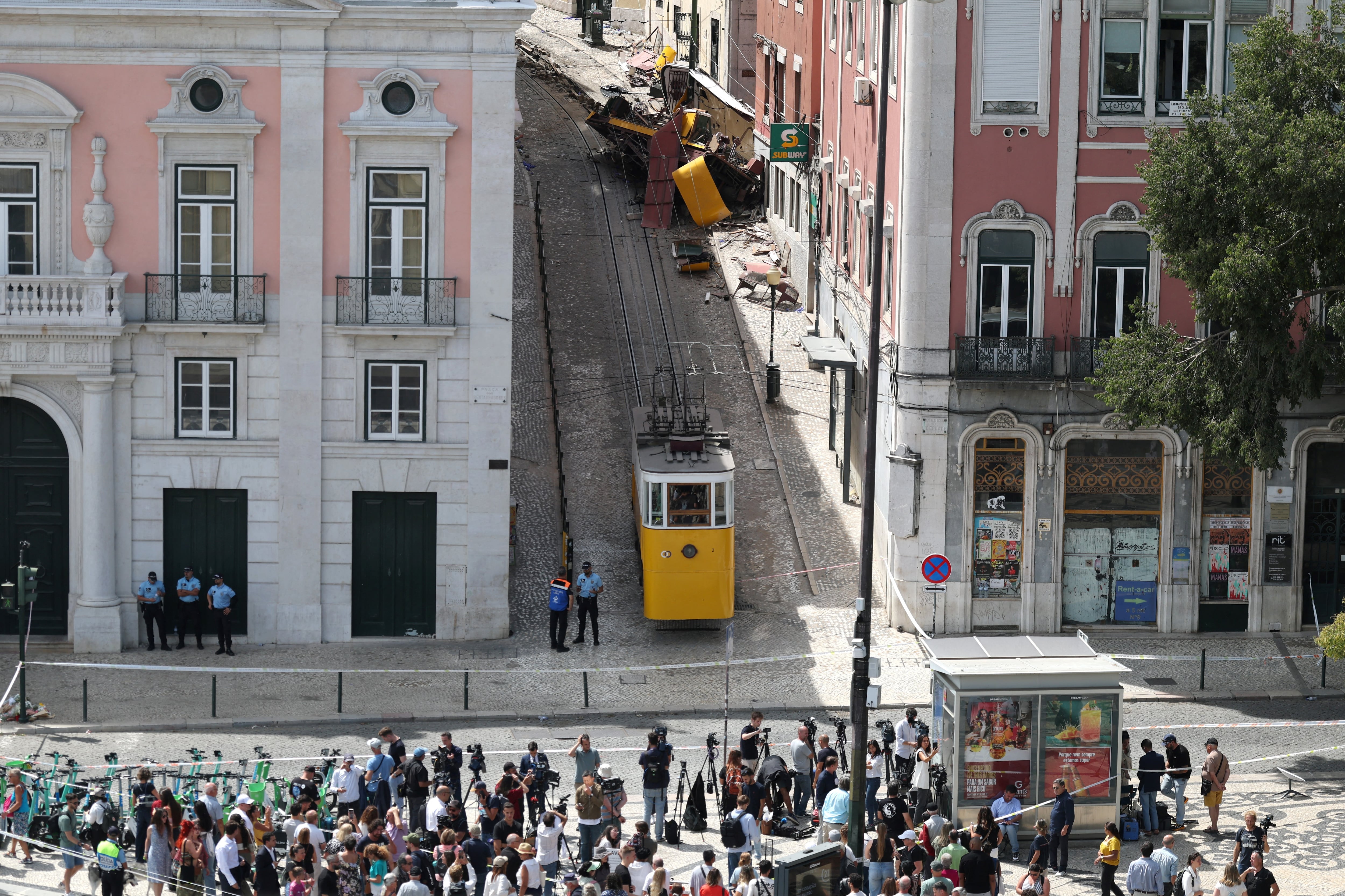 La gente se reúne para ver los restos (arriba) del Funicular Gloria el día después de un accidente que le generó la muerte a 16 personas en Lisboa, el 4 de septiembre de 2025
