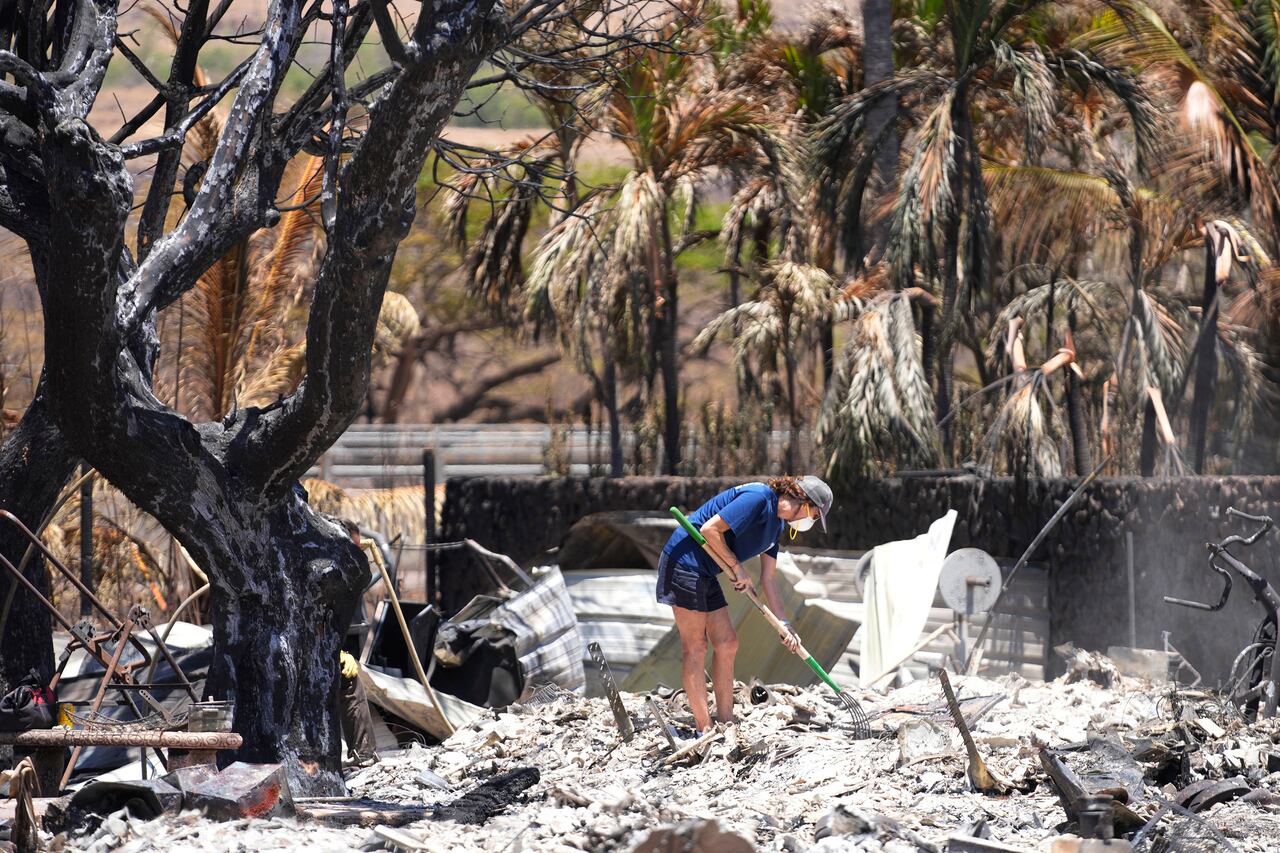Una mujer excava entre los escombros de una casa destruida por el incendio forestal