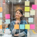 Mujer latinoamericana pensando en ideas creativas de ventas en la oficina para poner en un gráfico de pared