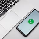 In this photo illustration a WhatsApp logo seen displayed on a smartphone screen on a desk next to a Macbook in Athens, Greece on November 14, 2022. (Photo Illustration by Nikolas Kokovlis/NurPhoto via Getty Images)