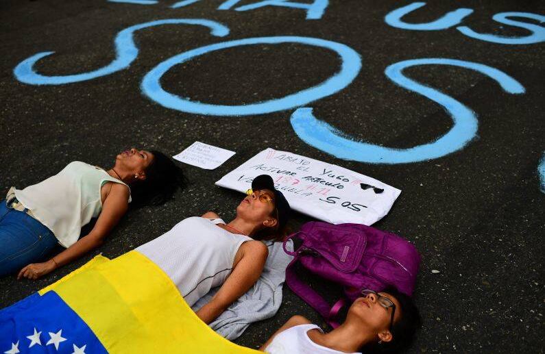  Los opositores al gobierno del presidente venezolano Nicolás Maduro con una bandera nacional venezolana bloquean una calle mientras se manifiestan en Caracas el 12 de marzo de 2019. FOTO: RONALDO SCHEMIDT/AFP