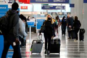A traveler wears a mask as she walks through Terminal 3 at O'Hare International Airport in Chicago, Sunday, Nov. 29, 2020. Friday's total of new cases is the next-to-lowest daily number in the past 12 days, but Illinois state officials are bracing for another surge after many people around the country traveled for Thanksgiving and celebrated with family and friends. (AP Photo/Nam Y. Huh)
