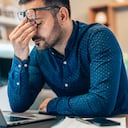 Joven empresario cansado que trabaja en casa usando una computadora portátil y luciendo ansioso