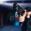 Foto borrosa de un militar caucásico experimentado vestido con uniforme negro sosteniendo la pistola con una mano robo