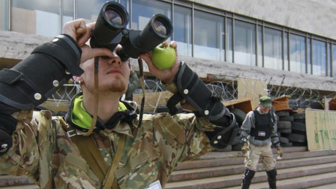 Un manifestante prorruso usa unos prismáticos durante una protesta frente a un edificio de la administración regional de Donetsk ocupado en la citada ciudad ucraniana