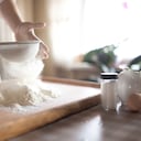 mujer joven tamizando la harina en un tazón en la cocina