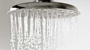 Gotas de agua cayendo de un cabezal de ducha de metal.