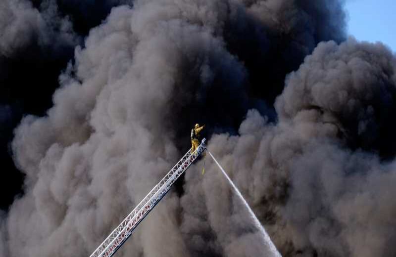 Un bombero solitario responde a un incendio en Los Ángeles. A su espalda, la gigantesca columna de humo de la conflagración.