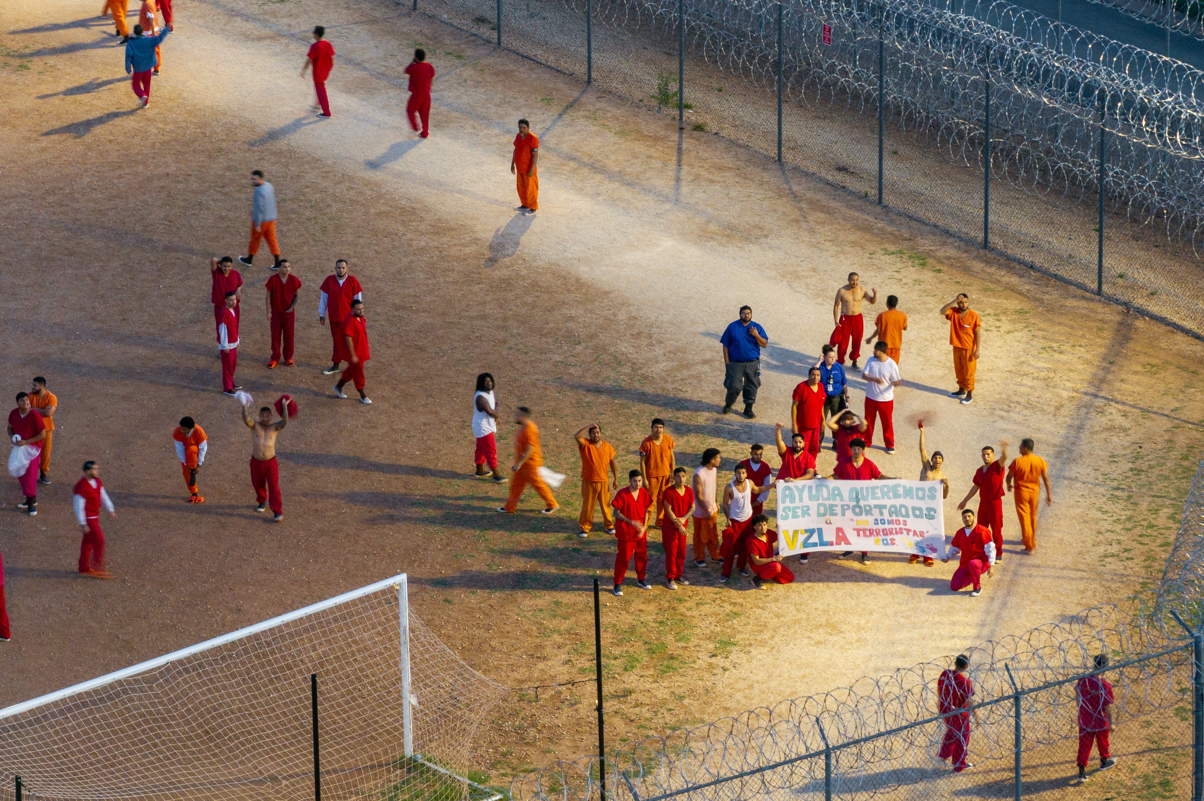 En una vista aérea, se observa a reclusos en el patio del Centro de Detención Bluebonnet con una pancarta que dice "Ayuda, queremos ser deportados, no somos terroristas, S.O.S.",