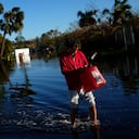 José Cruz, de 13 años, lleva un bidón vacío a través de las aguas de inundación que retroceden frente a su casa mientras su familia sale a buscar suministros, tres días después del paso del huracán Ian, en Fort Myers, Florida