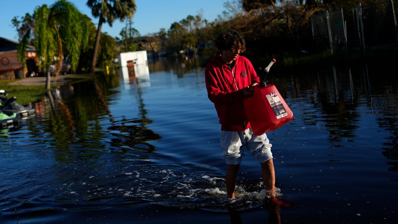 José Cruz, de 13 años, lleva un bidón vacío a través de las aguas de inundación que retroceden frente a su casa mientras su familia sale a buscar suministros, tres días después del paso del huracán Ian, en Fort Myers, Florida