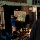 Pavel Sheludko muestra uno de los cuadros que vende a un comprador en un mercado callejero en Kiev, Ucrania, el 9 de julio de 2023. El vecindario de Pochaina de la capital ucraniana cobra vida cada fin de semana cuando cientos de personas acuden en masa a su famoso mercadillo en busca de tesoros. (AP Foto/Jae C. Hong)