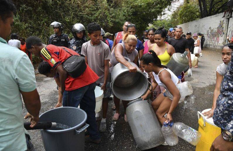 Los miembros de la Policía Nacional Bolivariana ayudan a organizar la distribución de agua potable a los residentes del barrio de San Agustín en Caracas. FOTO: Yuri CORTEZ/AFP