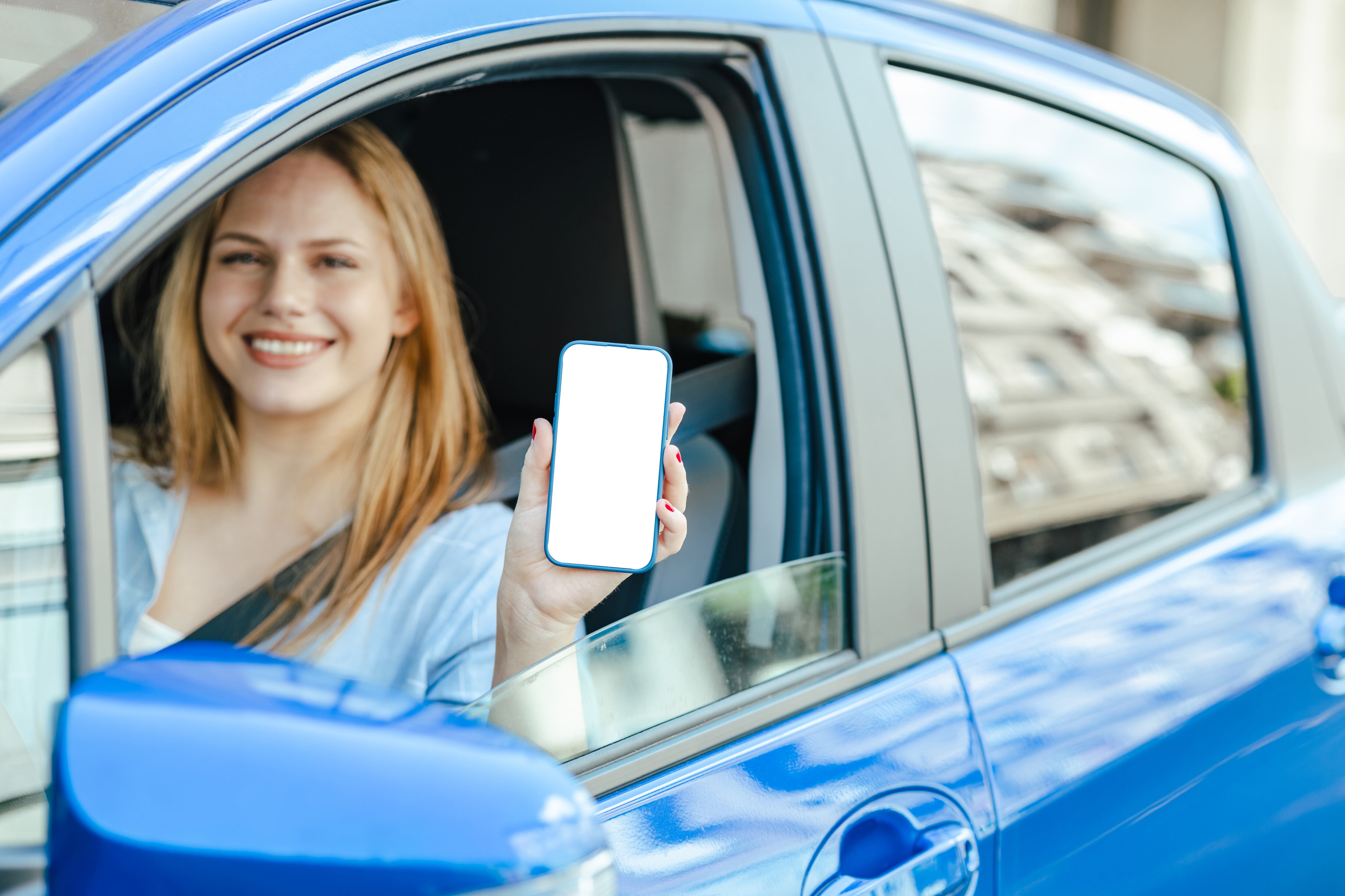 Mujer joven mostrando su teléfono móvil a través de la ventanilla del coche. Croma.