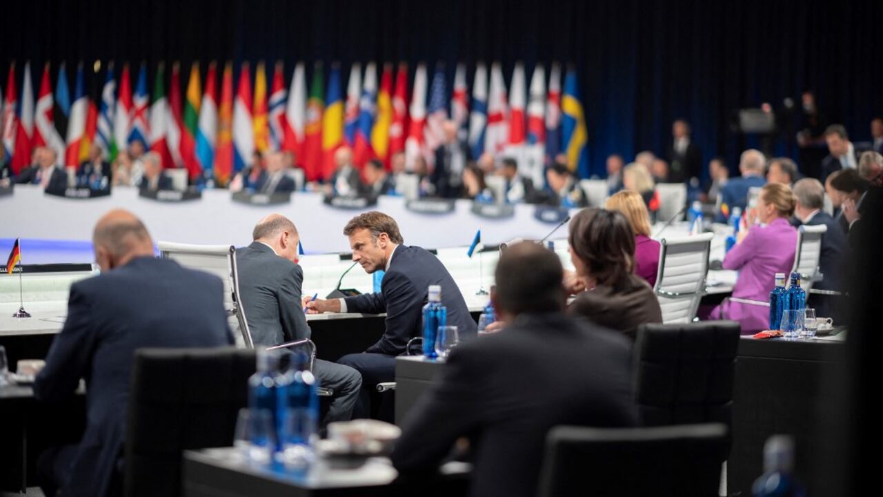 El presidente francés, Emmanuel Macron, habla con el canciller de Alemania, Olaf Scholz, al comienzo de la segunda sesión plenaria de la cumbre de la OTAN en el centro de congresos de Ifema en Madrid, el 29 de junio de 2022. (Foto de Eliot BLONDET / POOL / AFP)