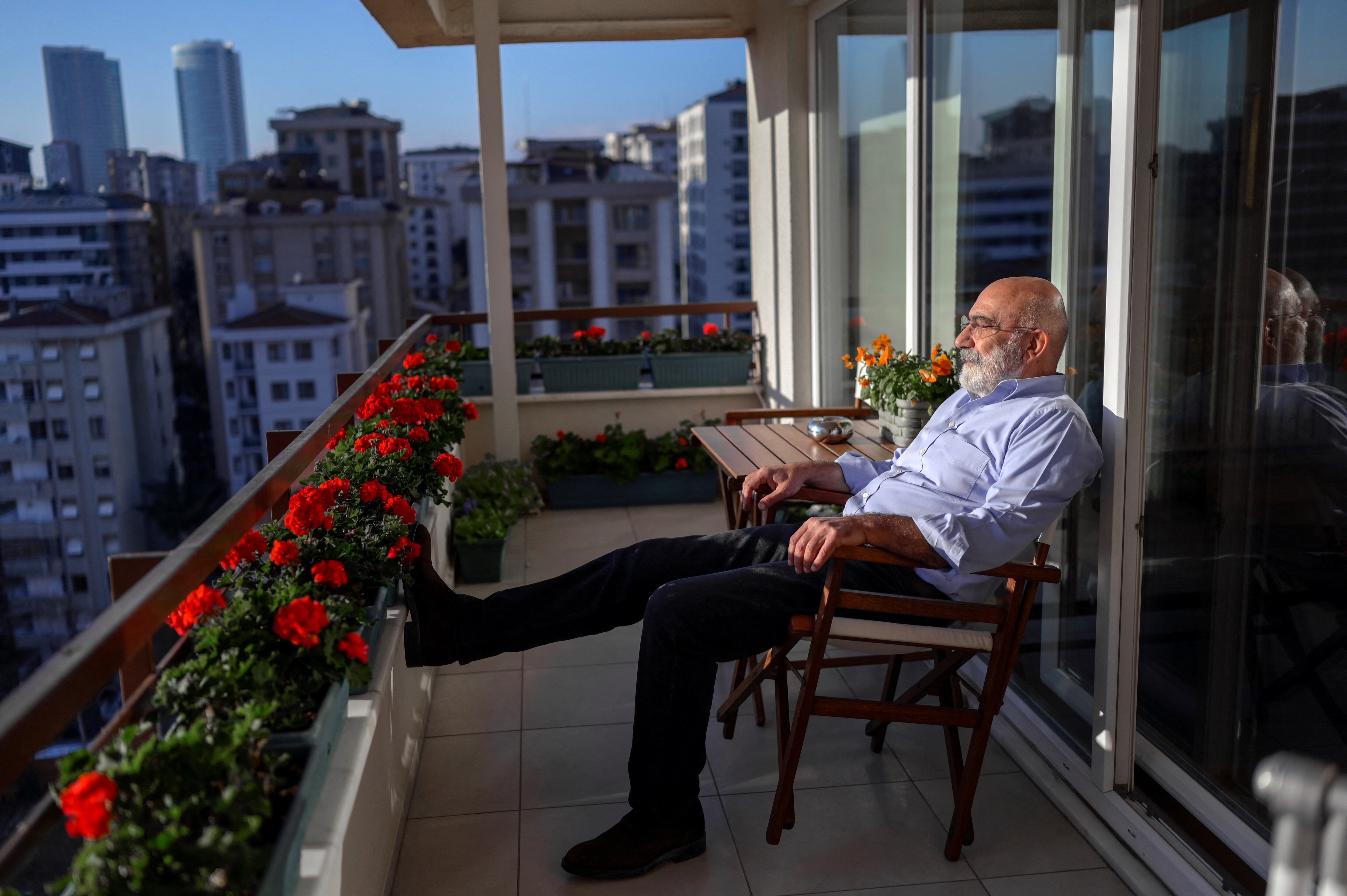 Ahmet Altan sits on his balcony during an interview at his home in Istanbul on January 5, 2022. - Freed after nearly five years in jail for alleged involvement in a failed coup, Turkish journalist and author Ahmet Altan, 71, now counts time by the number of books he has left to write. (Photo by BULENT KILIC / AFP)