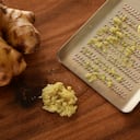 Jengibre rallado fresco sobre tabla de madera.