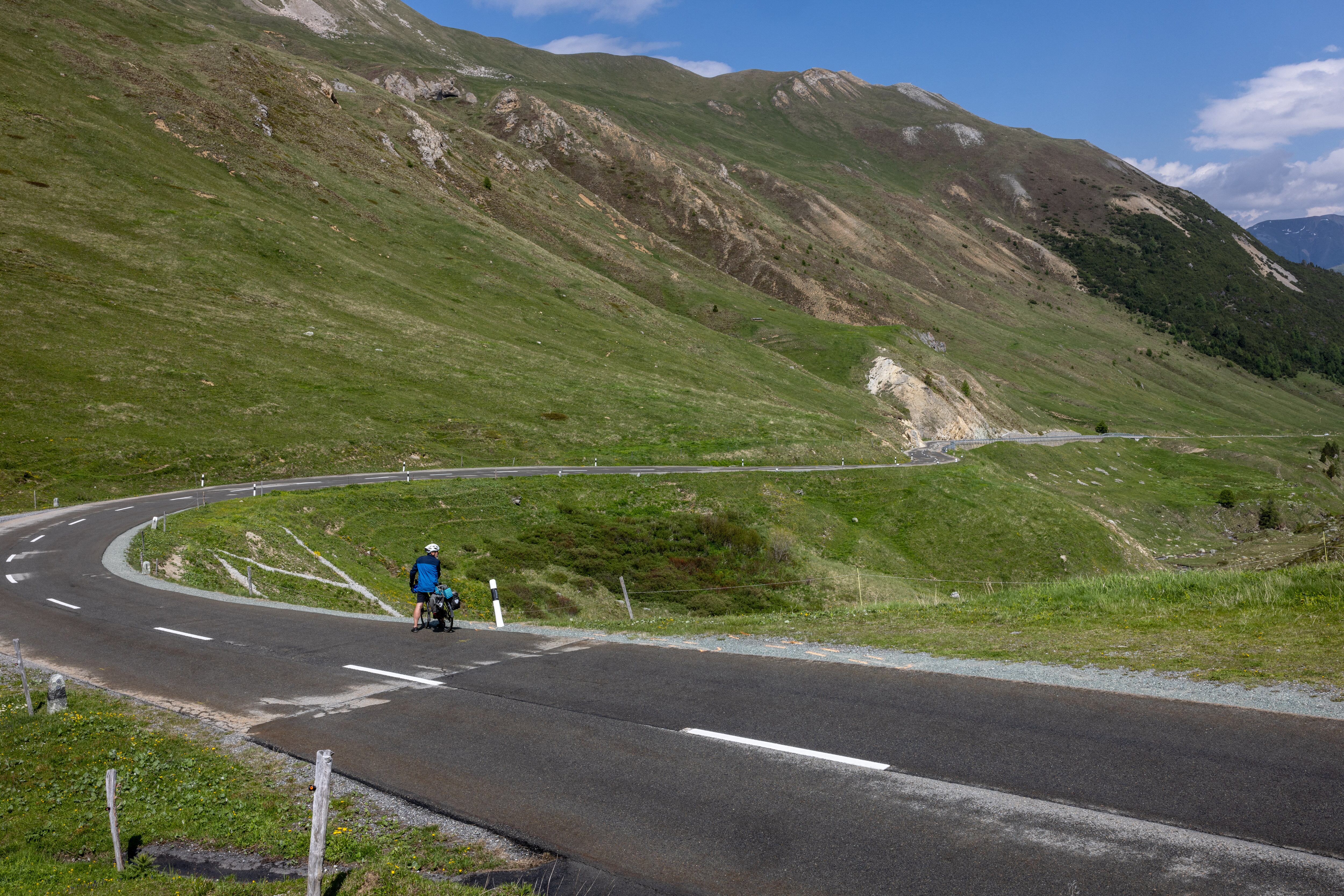 A rider looks on June 16, 2023 at the curve were Swiss rider Gino Maeder fell during a high-speed descent of the fifth stage of the Tour of Switzerland cycling rave above La Punt-Chamues-ch, far-eastern Switzerland. Gino Maeder, 26, has died from the injuries he sustained when he plunged into a ravine his team Bahrain-Victorious said on June 16, 2023. Maeder fell during a high-speed descent on the fifth stage between Fiesch and La Punt on June 15, 2023 after an exhausting day marked by three ascents over 2,000 metres altitude. (Photo by ARND WIEGMANN / AFP)