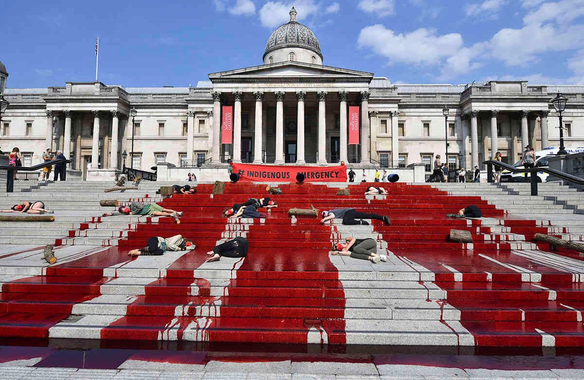 Tinta roja cubre los escalones de la Galería Nacional de Arte de Londres mientras los manifestantes del movimiento Extinction Rebellion simbólicamente se hacen los muertos, en una acción de solidaridad con las comunidades indígenas en Brasil, el domingo 9 de agosto de 2020. El grupo de presión internacional Extinction Rebellion pide que se brinde ayuda a las comunidades indígenas que están muriendo por el coronavirus en Brasil. Foto: Dominic Lipinski / PA vía AP 