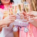 Amigos tintineo de vasos en la fiesta de bienvenida al bebé, primerísimos en el vino espumoso