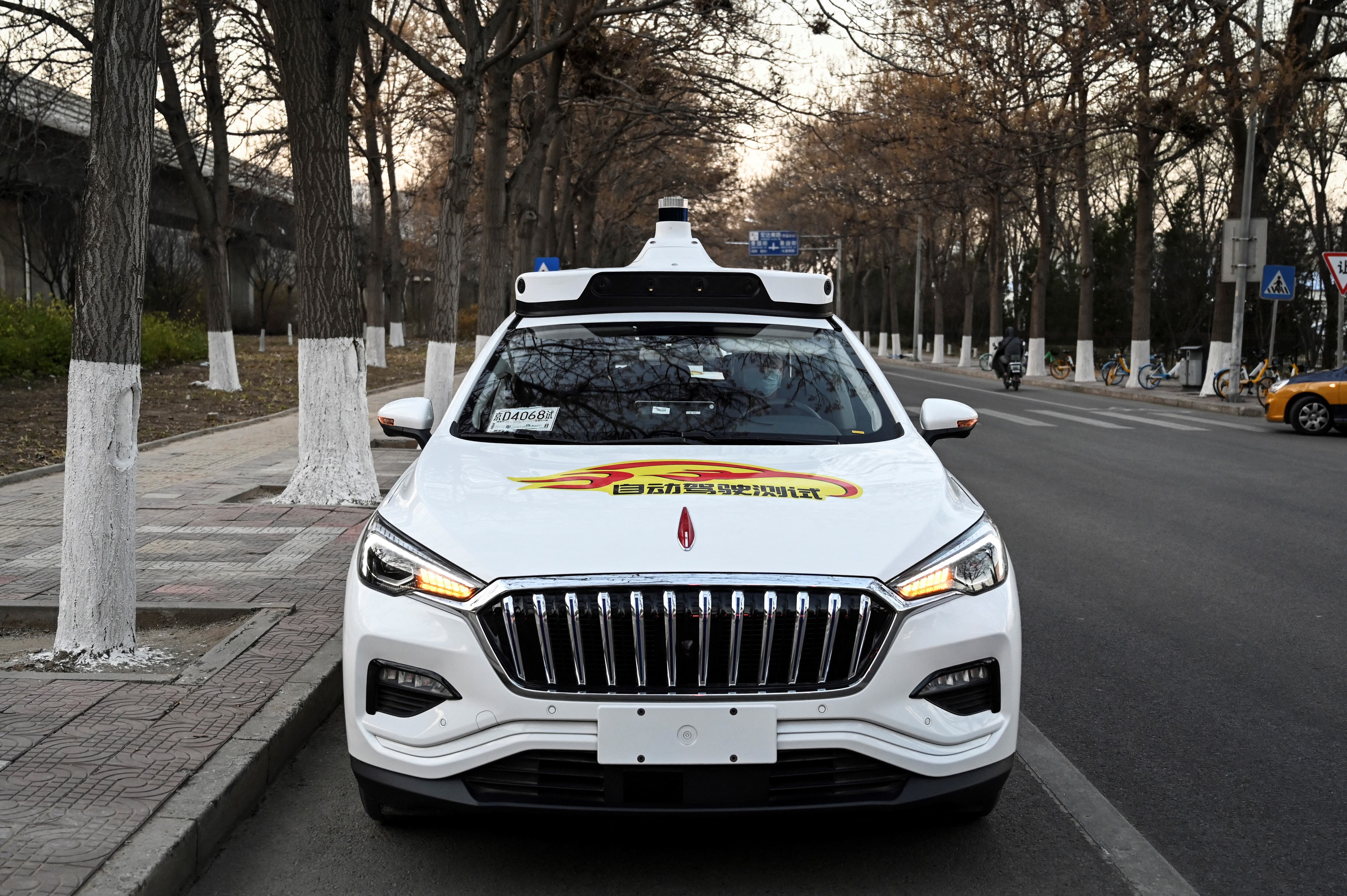 La foto tomada el 25 de noviembre de 2021 muestra un taxi autónomo Apollo Go en una calle de Yizhuang, una ciudad del distrito de Daxing, en los suburbios del sureste de Beijing. - Beijing aprobó esta semana sus primeros taxis autónomos para uso comercial, trayendo decenas de los llamados "robotaxis" a las calles de la capital china. Un empleado de la empresa de taxis también se sienta en la parte delantera del automóvil en caso de que sea necesaria una intervención repentina, pero el vehículo se conduce solo. (Foto de Jade GAO / AFP) / PARA IR CON AFP STORY CHINA-ECONOMY-TRANSPORT-TECHNOLOGY