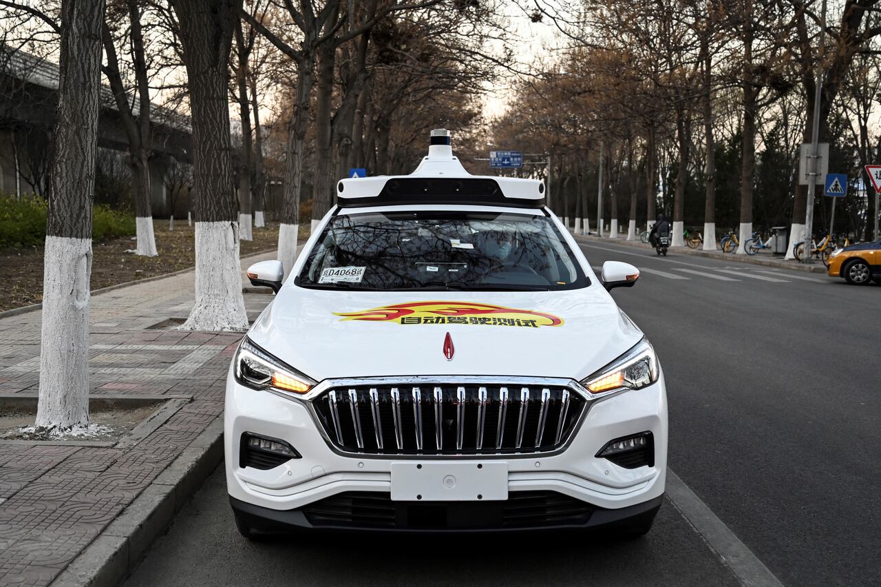 La foto tomada el 25 de noviembre de 2021 muestra un taxi autónomo Apollo Go en una calle de Yizhuang, una ciudad del distrito de Daxing, en los suburbios del sureste de Beijing. - Beijing aprobó esta semana sus primeros taxis autónomos para uso comercial, trayendo decenas de los llamados "robotaxis" a las calles de la capital china. Un empleado de la empresa de taxis también se sienta en la parte delantera del automóvil en caso de que sea necesaria una intervención repentina, pero el vehículo se conduce solo. (Foto de Jade GAO / AFP) / PARA IR CON AFP STORY CHINA-ECONOMY-TRANSPORT-TECHNOLOGY