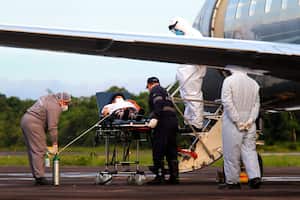 Healthcare workers and military prepare to board a COVID-19 patient onto an air force plane, at the Ponta Pelada Airport, in Manaus, Amazonas state, Brazil, Friday, Jan. 15, 2021. Some hope for Manaus, an isolated city of 2 million people, landed in a Brazilian air force plane on Friday with 6,000 liters of oxygen that are being distributed to hospitals. But as the pandemic hits hard, locals wonder how long the supply will last. (AP Photo/Edmar Barros)