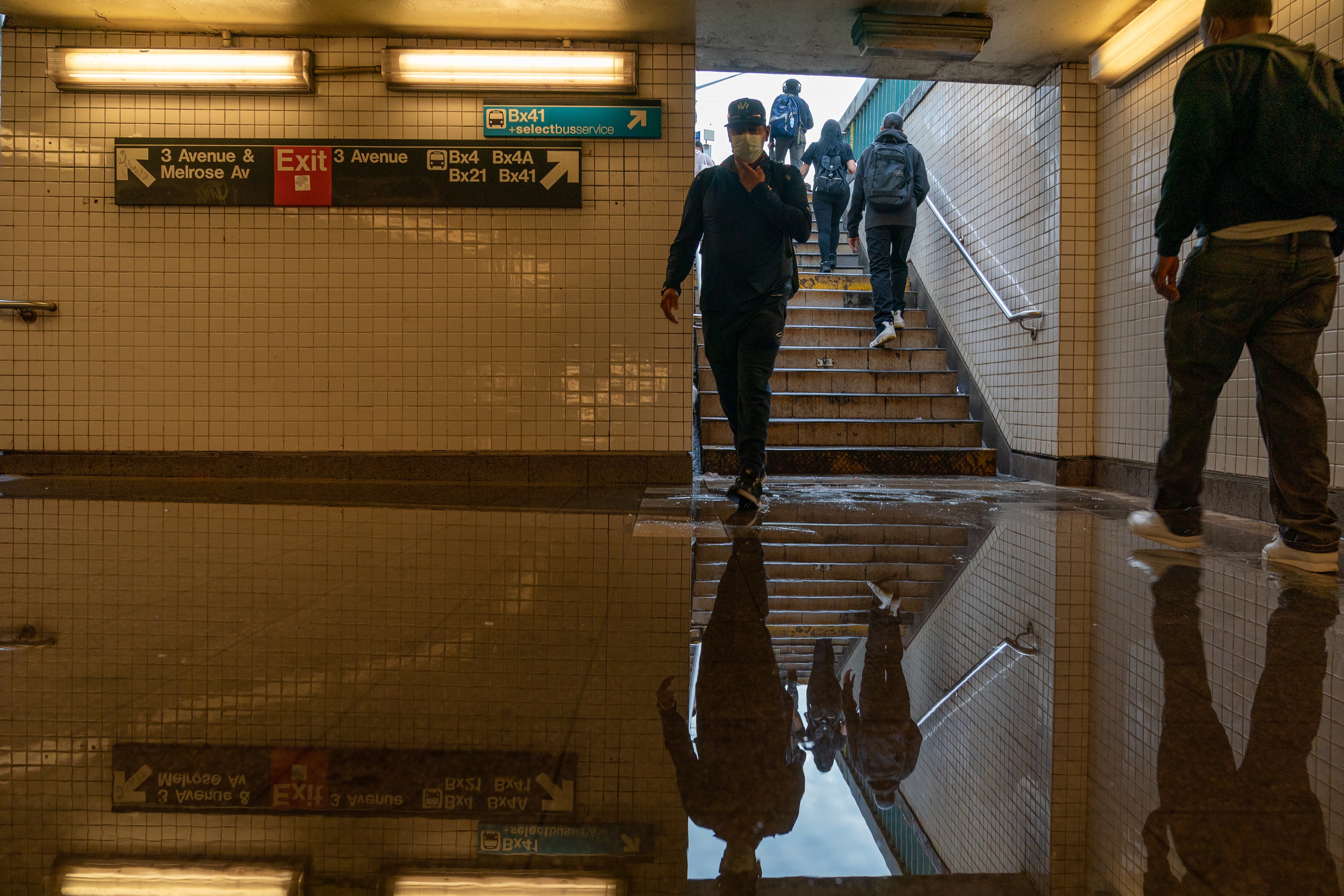 Pasajeros entran en una estación de metro inundada de la 3.ª Avenida y la calle 149, con el servicio interrumpido debido a las intensas lluvias.