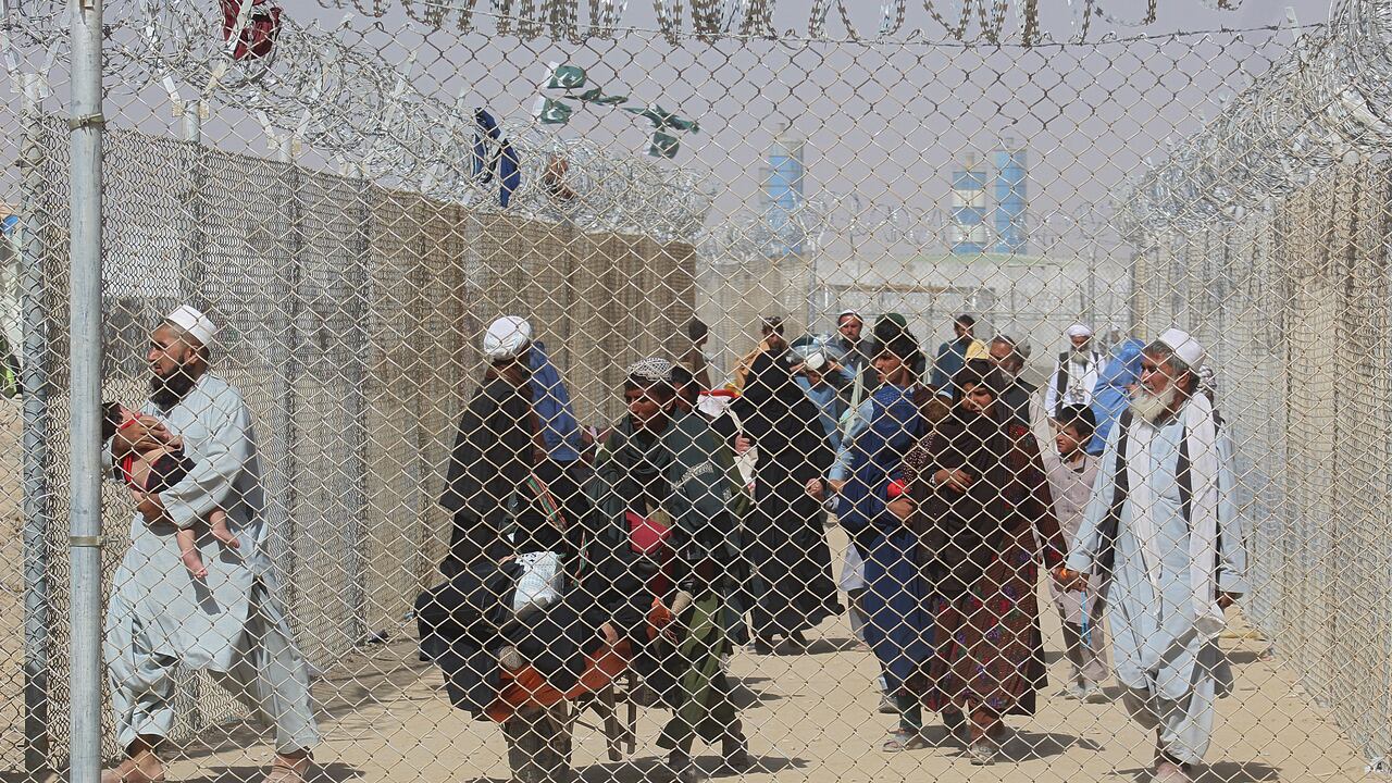 Afghan people walk inside a fenced corridor as they enter Pakistan at the Pakistan-Afghanistan border crossing point in Chaman on August 25, 2021 following the Taliban's stunning military takeover of Afghanistan. (Photo by - / AFP)