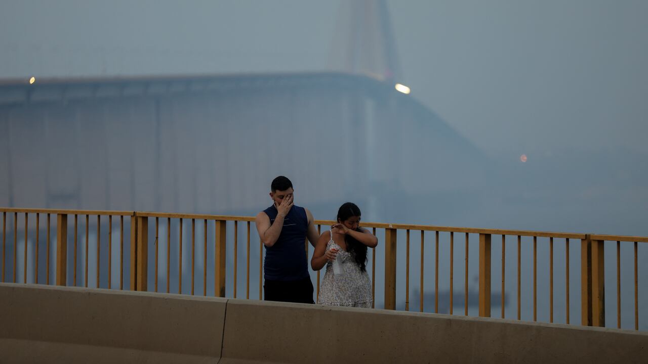 Una pareja camina por el puente del periodista Phelippe Daou mientras la neblina de humo de los incendios en la selva amazónica cubre el área de Manaos, estado de Amazonas, al norte de Brasil, el 13 de octubre de 2023. Manaos, la principal ciudad de la Amazonía brasileña, ha estado asfixiada desde hace varios días, cuando sus dos millones de habitantes se vieron envueltos por una nube tóxica formada por incendios provocados por "delincuentes", advirtió el viernes el Ministerio de Medio Ambiente. (Foto de Michael Dantas / AFP)