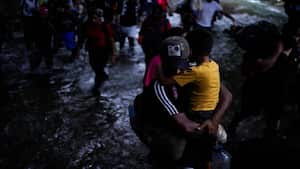 Un migrante venezolano lleva a su hijo mientras cruza el Tapón del Darién.