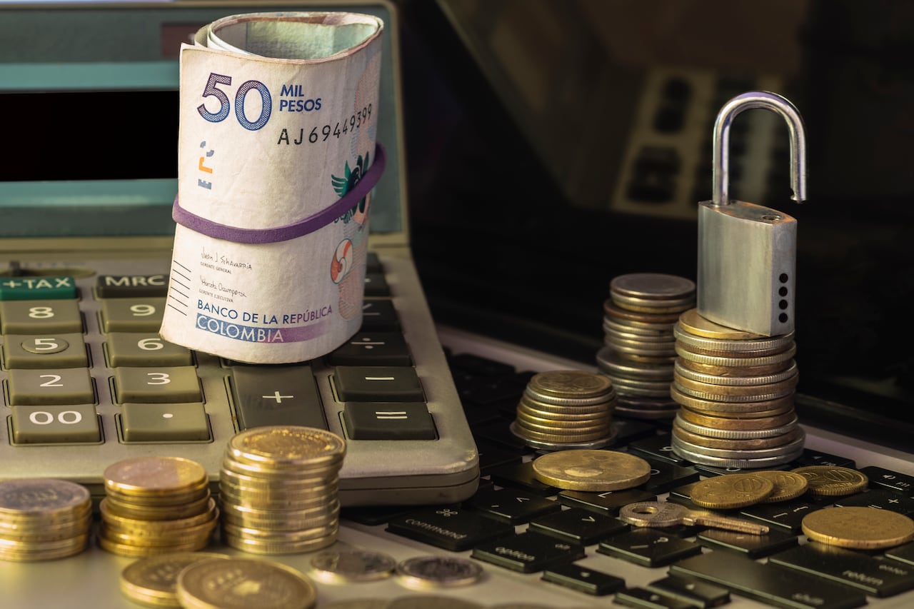 Pile and coins of Two Hundred Colombian Pesos with a calculator as a background. Income, expenses, taxes, financial data