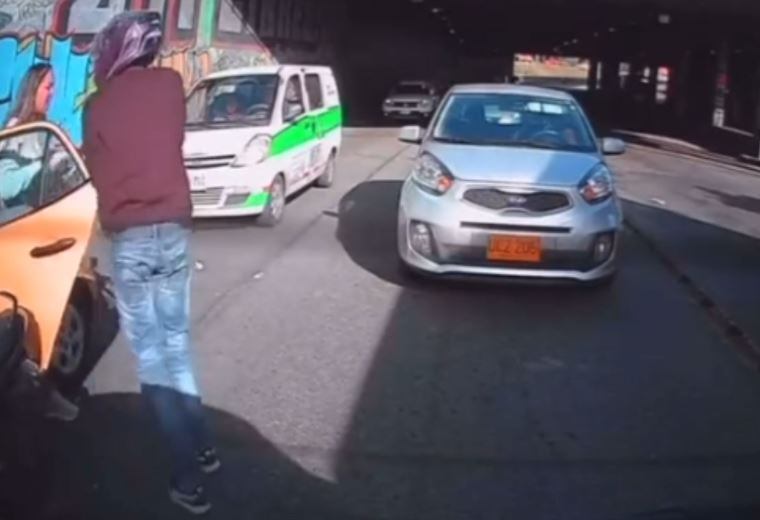 El ladrón obliga a la mujer a bajarse del taxi para robarle sus pertenencias.