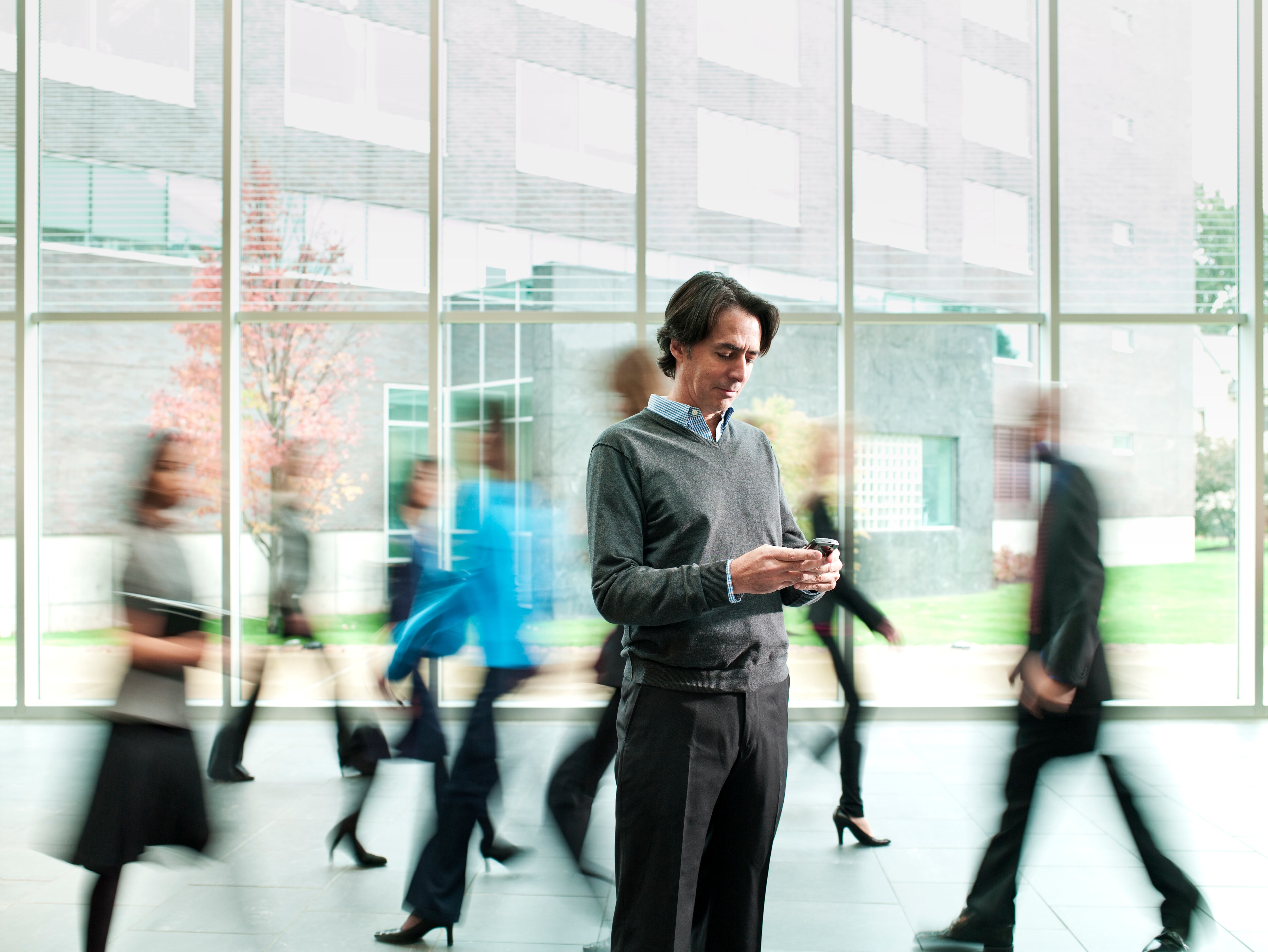 Hombre de negocios revisando su teléfono mientras la multitud pasa