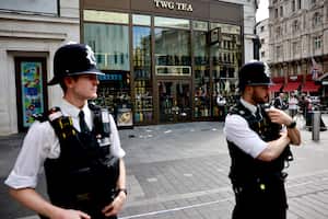 Una fotografía tomada el 12 de agosto de 2024 muestra a agentes de policía de pie junto a una zona acordonada en Leicester Square, Londres. Una mujer y una niña de 11 años fueron hospitalizadas el 12 de agosto después de ser apuñaladas en la famosa Leicester Square del centro de Londres, dijo la policía, añadiendo que un hombre había sido arrestado. (Foto de BENJAMIN CREMEL / AFP)