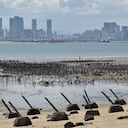 El horizonte de la ciudad de Xiamen, en la parte continental de China, se ve más allá de los picos anti-aterrizaje colocados a lo largo de la costa del islote Lieyu, en las islas Kinmen de Taiwán, que se encuentran a solo 3,2 km (dos millas) de la costa de China continental, el 10 de agosto de 2022. (Foto por Sam Yeh / AFP)