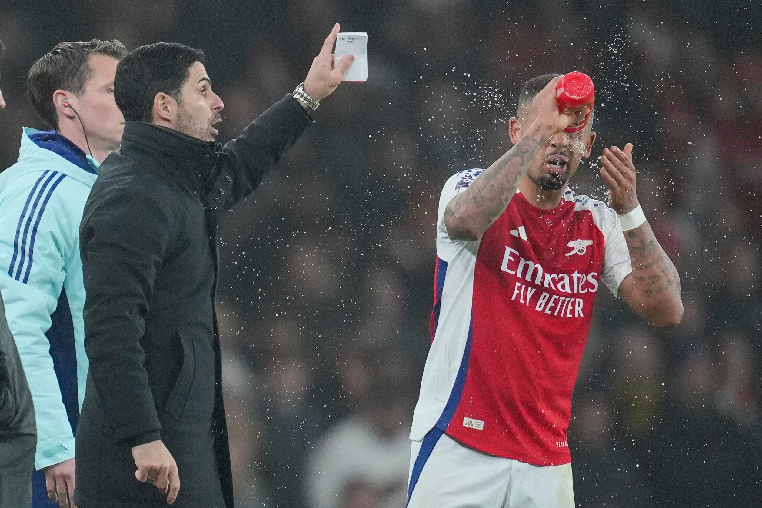 Arsenal's Gabriel Jesus splashes his face with water as Arsenal's manager Mikel Arteta gestures during the English Premier League soccer match between Arsenal and Ipswich at the Emirates Stadium in London, Friday, Dec. 27, 2024. (AP Photo/Kin Cheung)