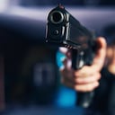 Foto borrosa de un militar caucásico experimentado vestido con uniforme negro sosteniendo la pistola con una mano robo