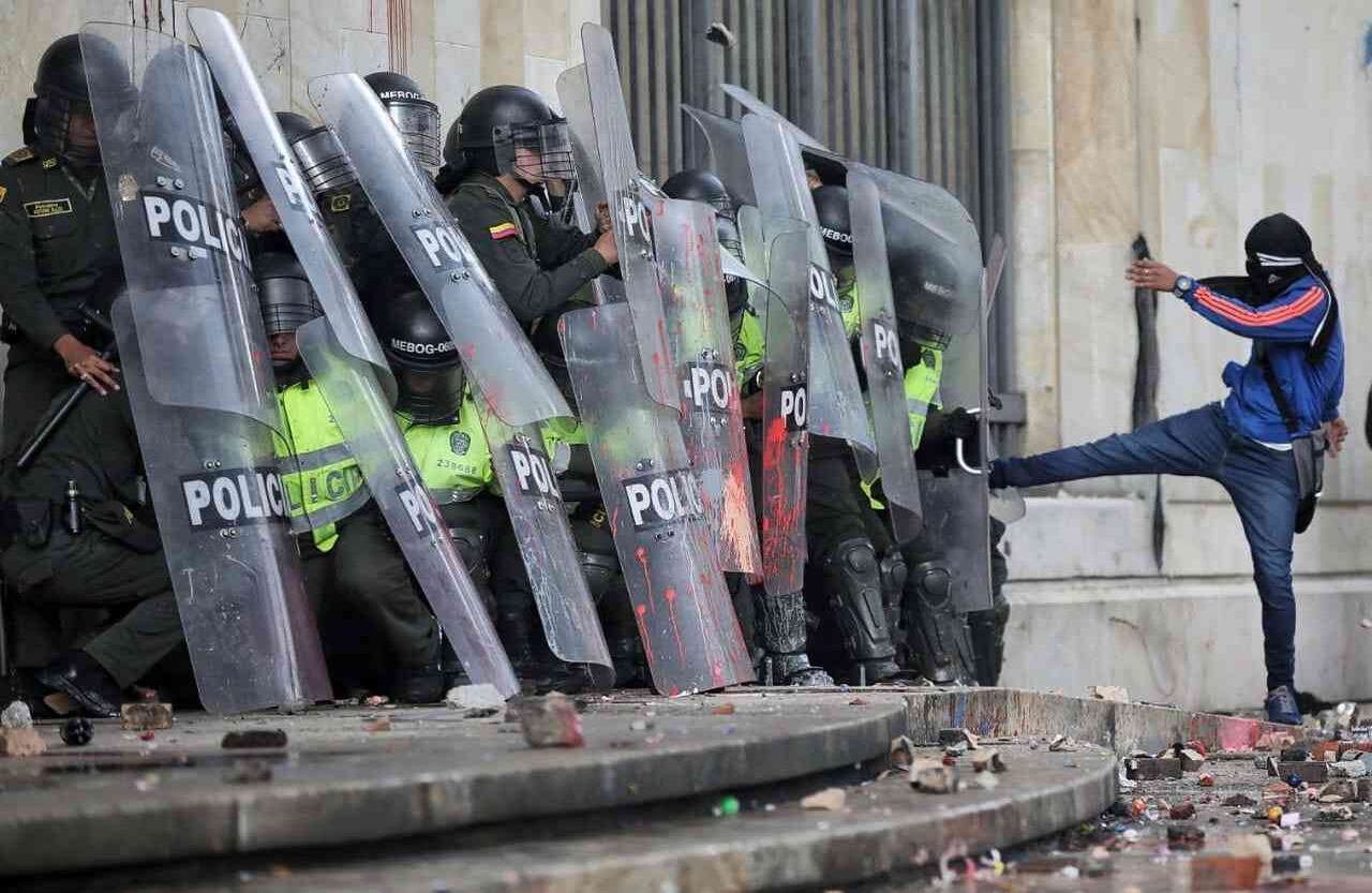 Un encapuchado patea a los policías arrinconados en el Palacio. 
