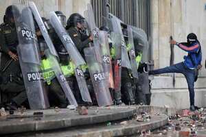 Un encapuchado patea a los policías arrinconados en el Palacio.