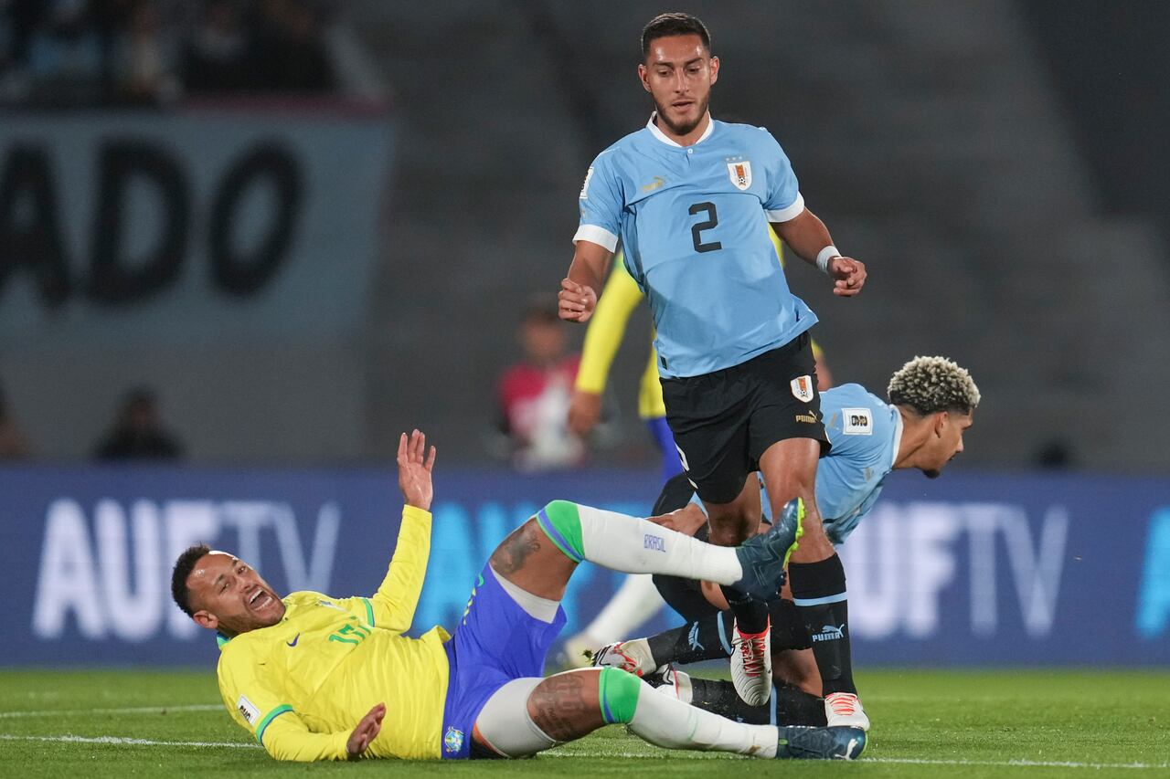 Brazil's Neymar falls while fighting for a ball with Uruguay's Sebastian Caceres during a qualifying soccer match for the FIFA World Cup 2026 at Centenario stadium in Montevideo, Uruguay, Tuesday, Oct. 17, 2023. (AP Photo/Matilde Campodonico)