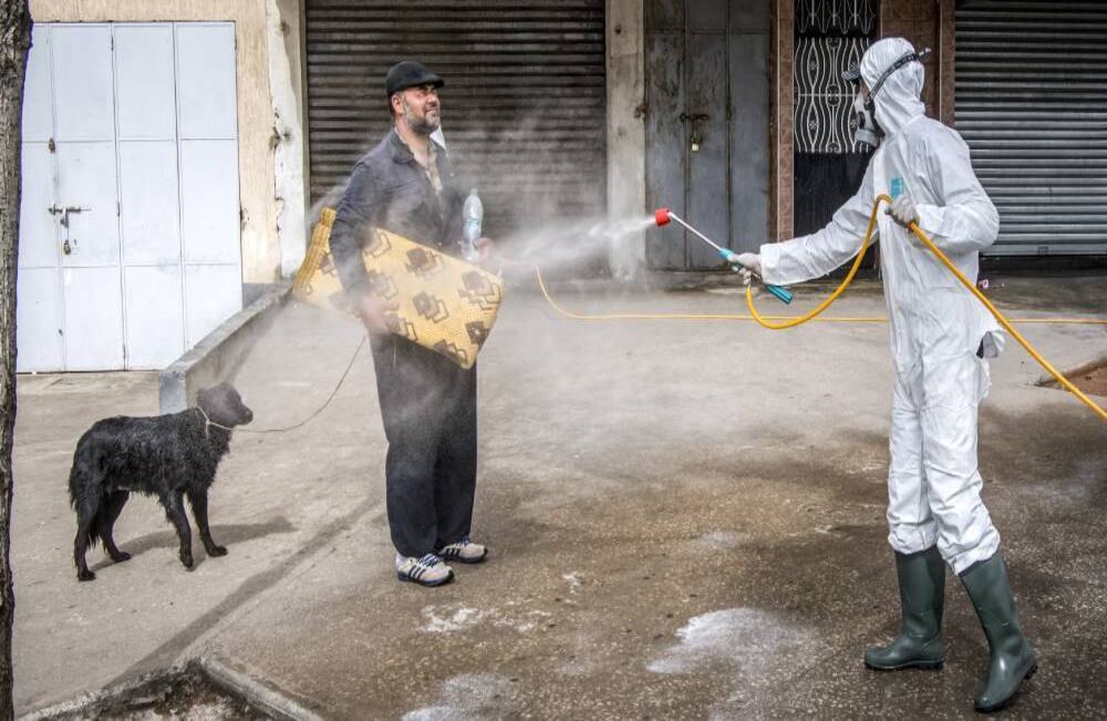 Un trabajador del ministerio de salud marroquí desinfecta a un hombre que paseaba a un perro y llevaba una colchoneta; sucedió en la capital, Rabat. El estado de emergencia de salud pública entró en vigencia en Marruecos, de mayoría musulmana, a fines del 20 de marzo, y las fuerzas de seguridad y el Ejército se ha desplegado en las calles para combatir la propagación de la enfermedad por coronavirus.  Se ha ordenado a las personas que se queden en sus hogares, también existen restricciones en el transporte público y los viajes entre ciudades. (22 de marzo) Foto: Fadel Senna /AFP