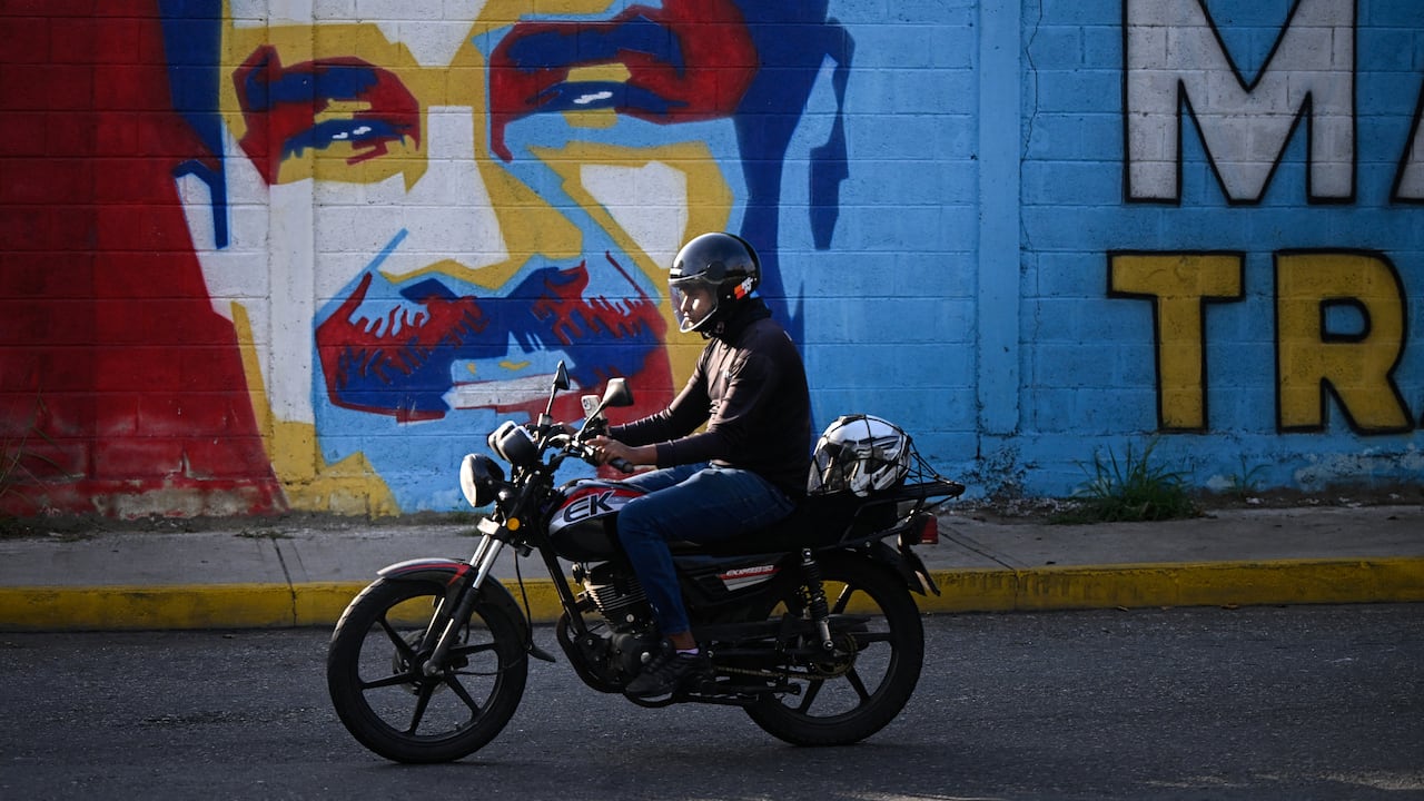 Un motociclista pasa junto a un mural del derrocado presidente de Venezuela, Nicolás Maduro, en Caracas, el 14 de mayo de 2026. (Photo by Federico PARRA / AFP)