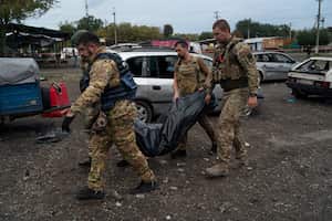 Militares ucranianos cargan una bolsa con el cuerpo de una persona después de un ataque ruso en Zaporizhzhia, Ucrania, el viernes 30 de septiembre de 2022.