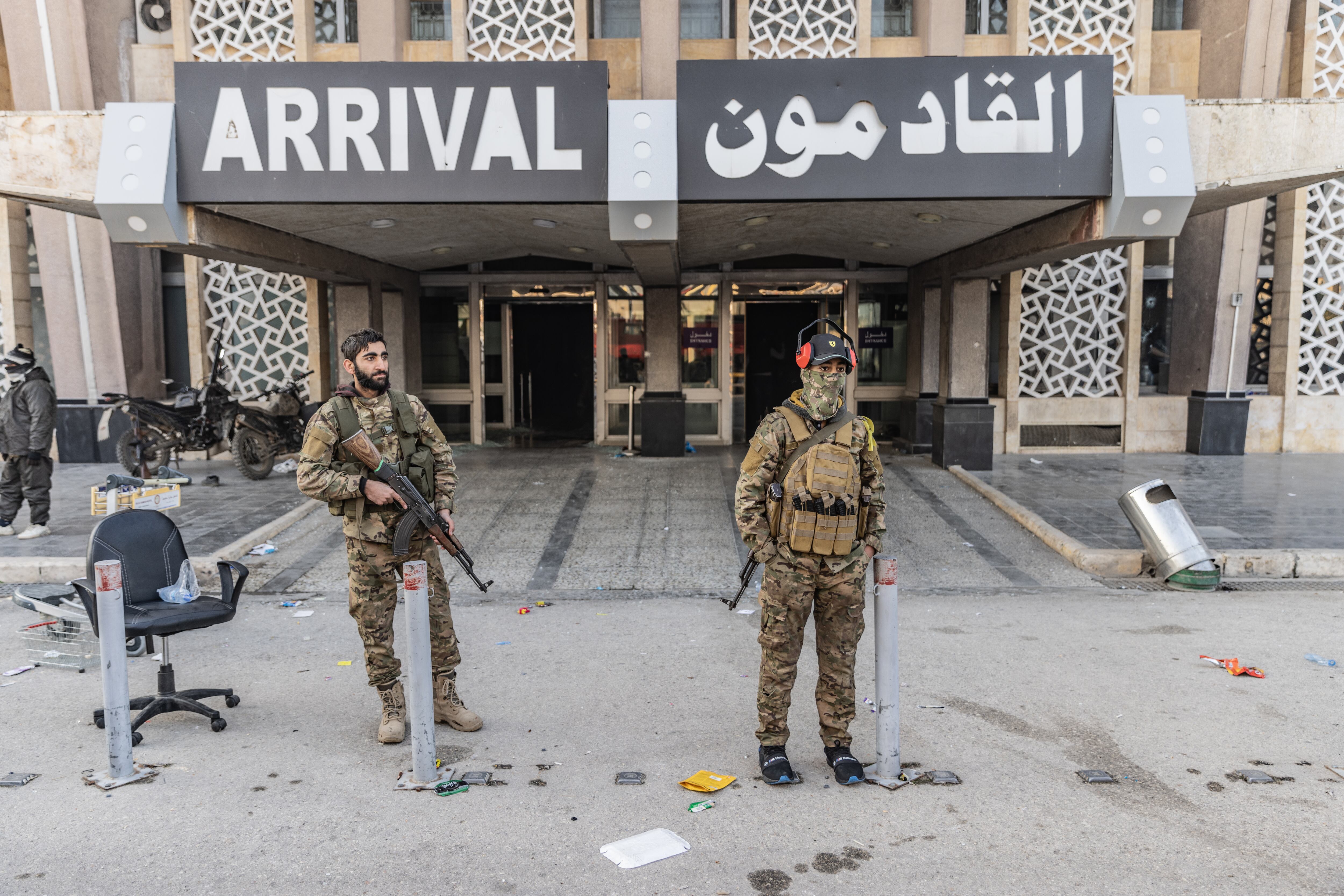 Miembros de la oposición armada siria se sitúan frente a la terminal de llegadas tras tomar el control del Aeropuerto Internacional de Alepo.