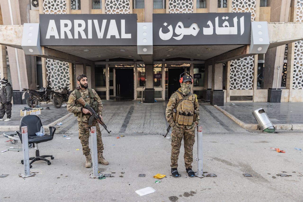 Miembros de la oposición armada siria se sitúan frente a la terminal de llegadas tras tomar el control del Aeropuerto Internacional de Alepo.